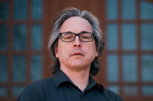 A portrait shows a man wearing glasses.
